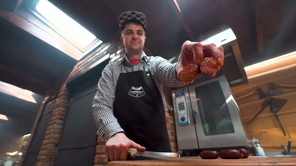 Lukáš Moucha u pultu nabízí plátky klobásy